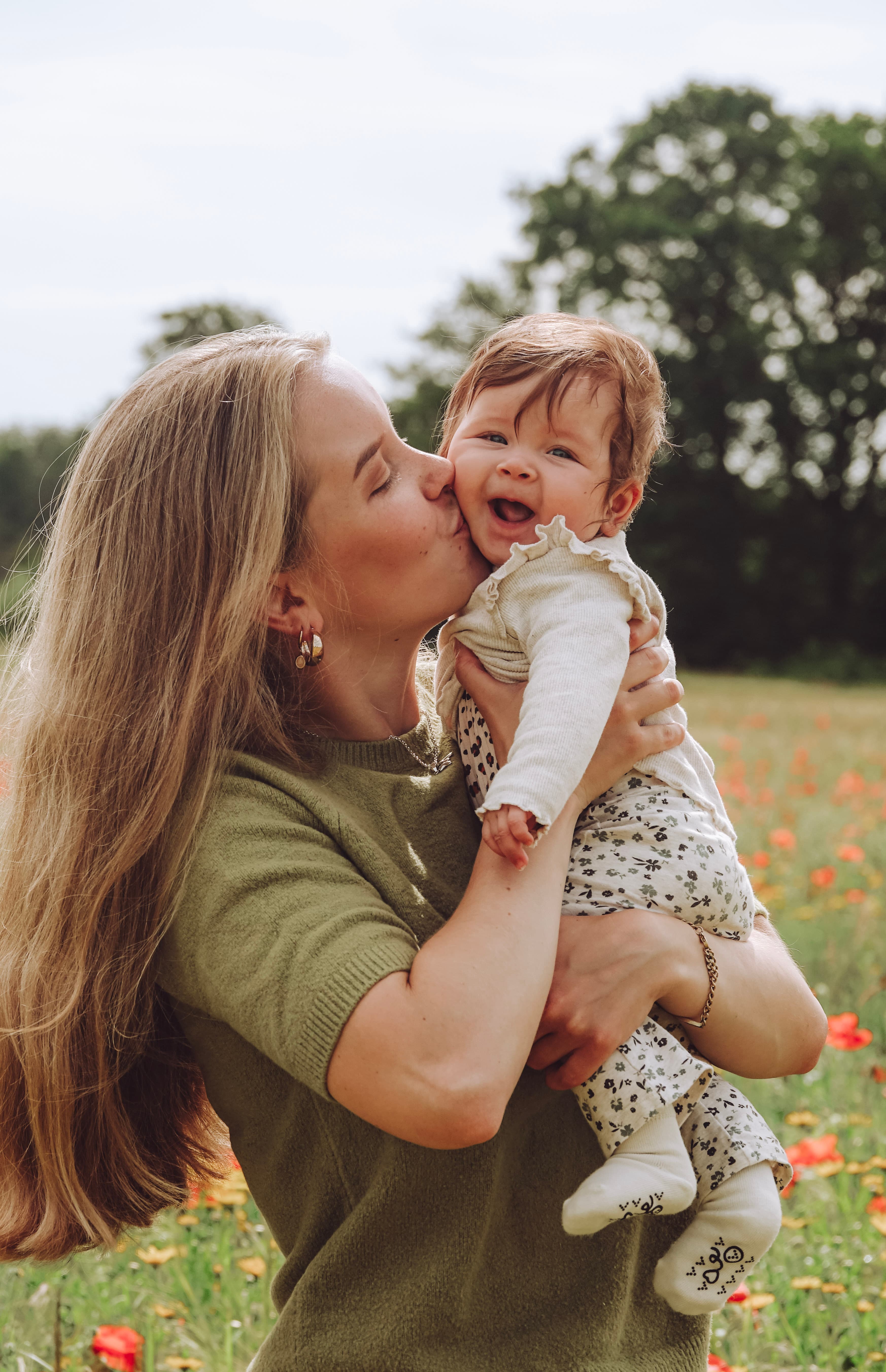 Moeder kust lachende baby in een klaprozenveldje